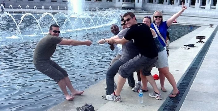 A group of people posing in front of a fountain.