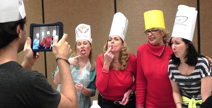 A group of women in chef hats taking a picture.