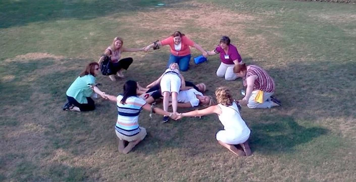 A group of people sitting in a circle on the grass.