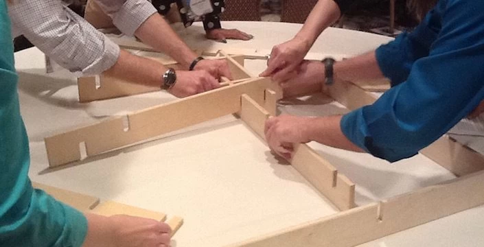 A group of people working on a wooden frame.