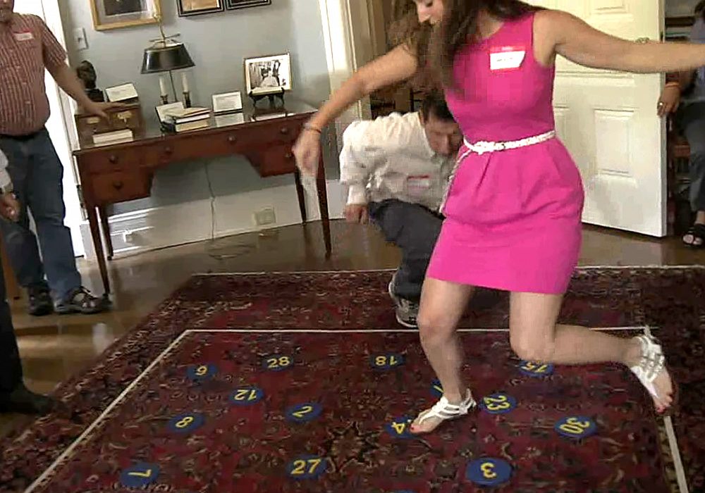 A woman in a pink dress standing on a rug in a living room.