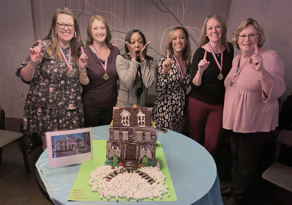 A group of women posing for a picture in front of a cake.