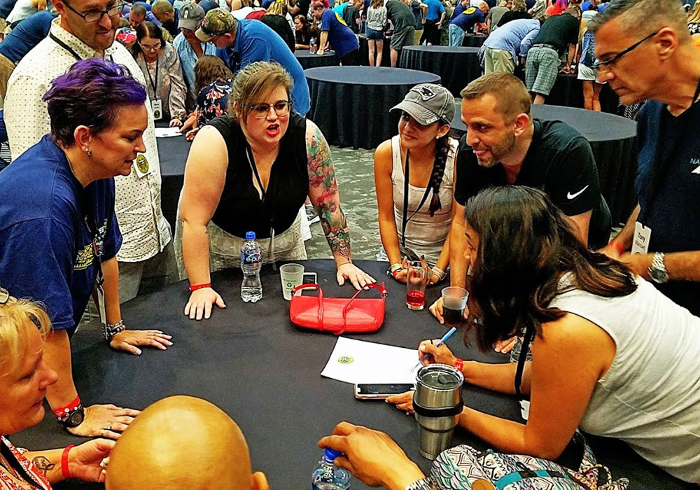 A group of people around a table signing autographs.