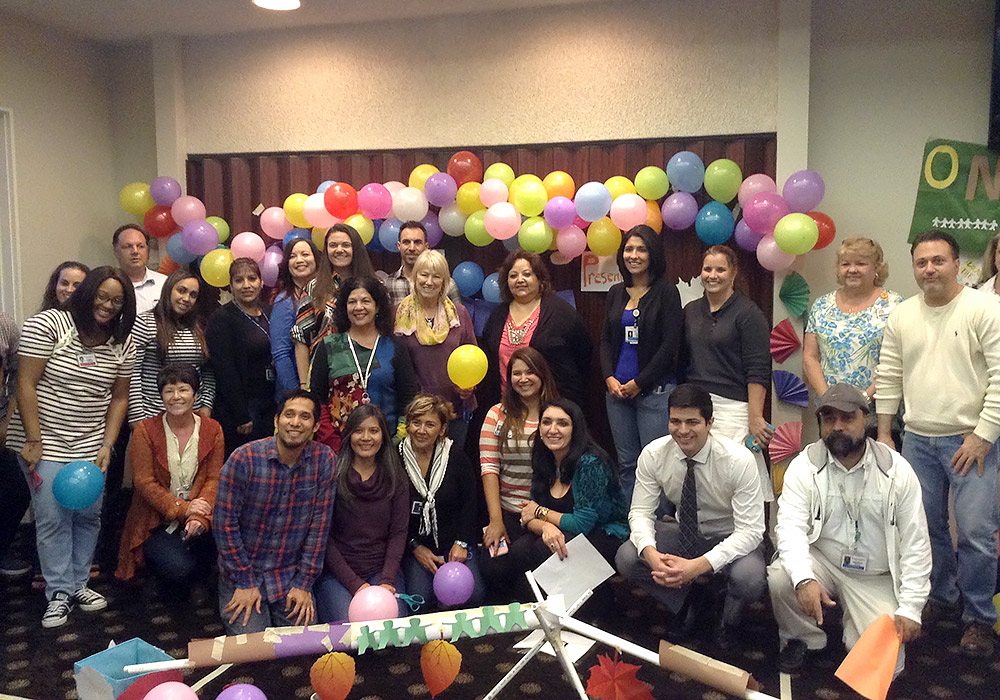 A group of people posing in front of balloons.