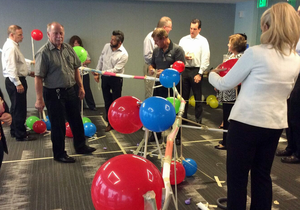 A group of people standing around a room full of balloons.