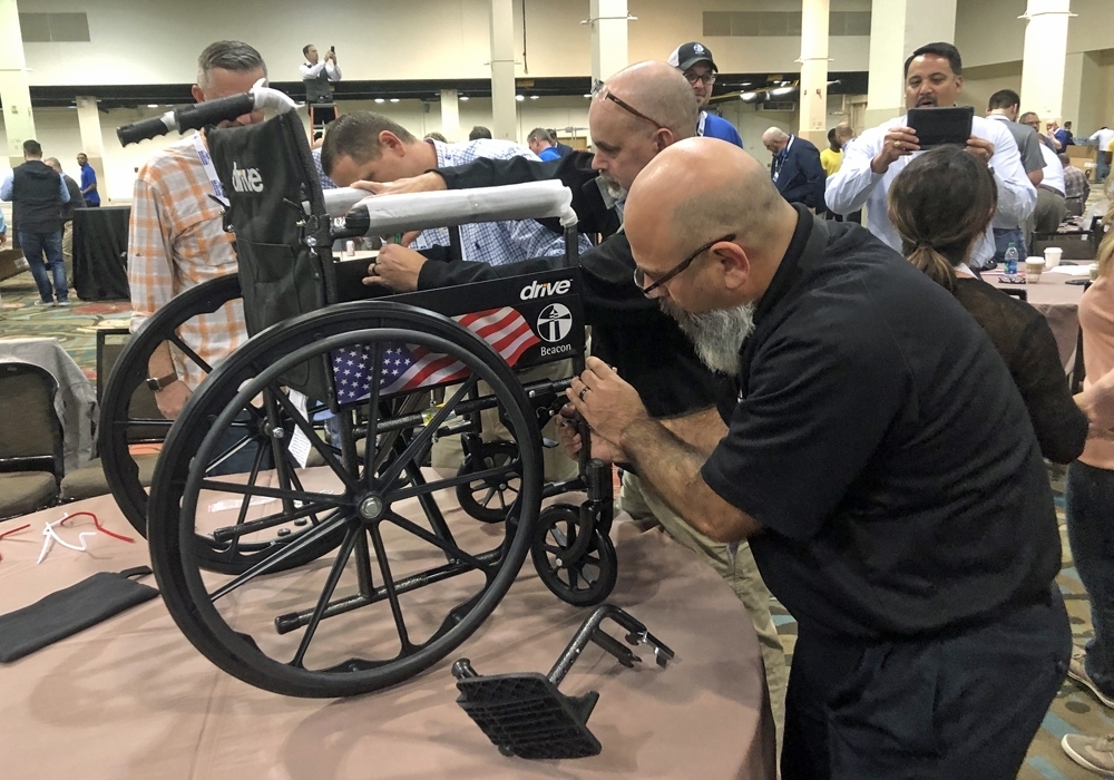 A group of people working on a wheelchair at a convention.