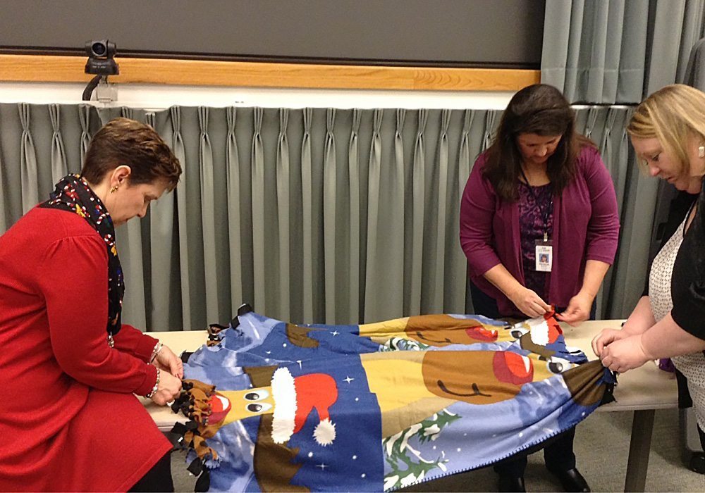 A group of women are putting together a santa claus blanket.