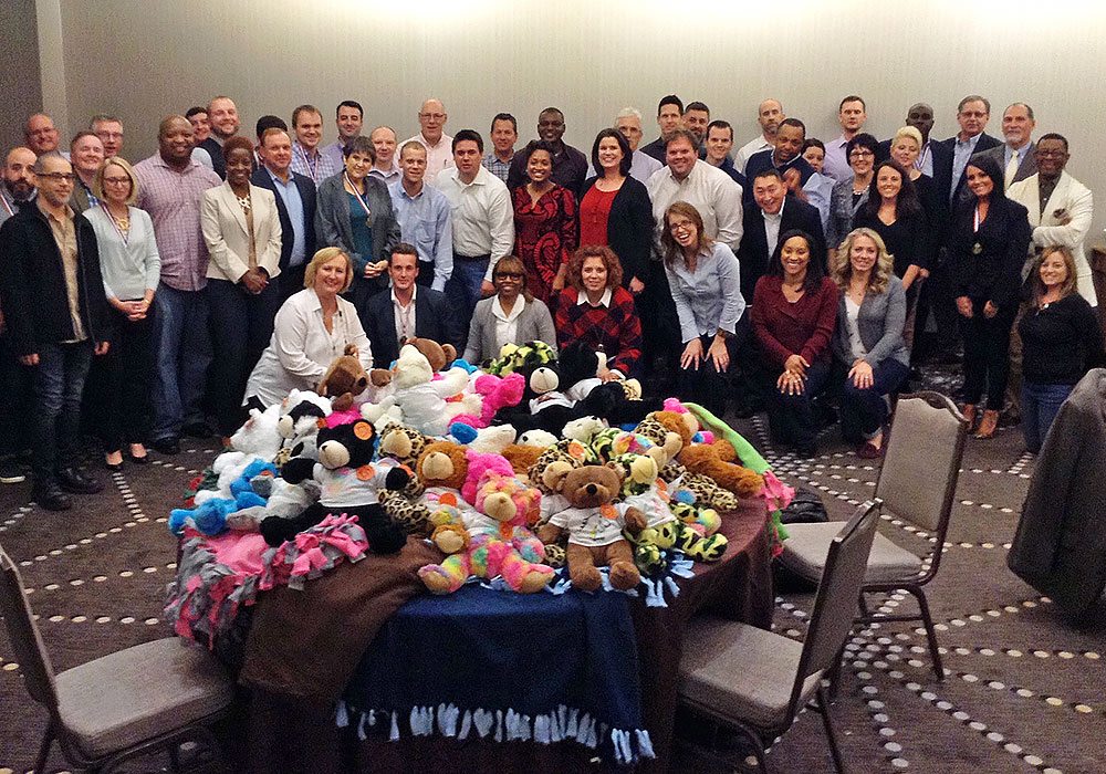 A group of people posing for a photo with stuffed animals.