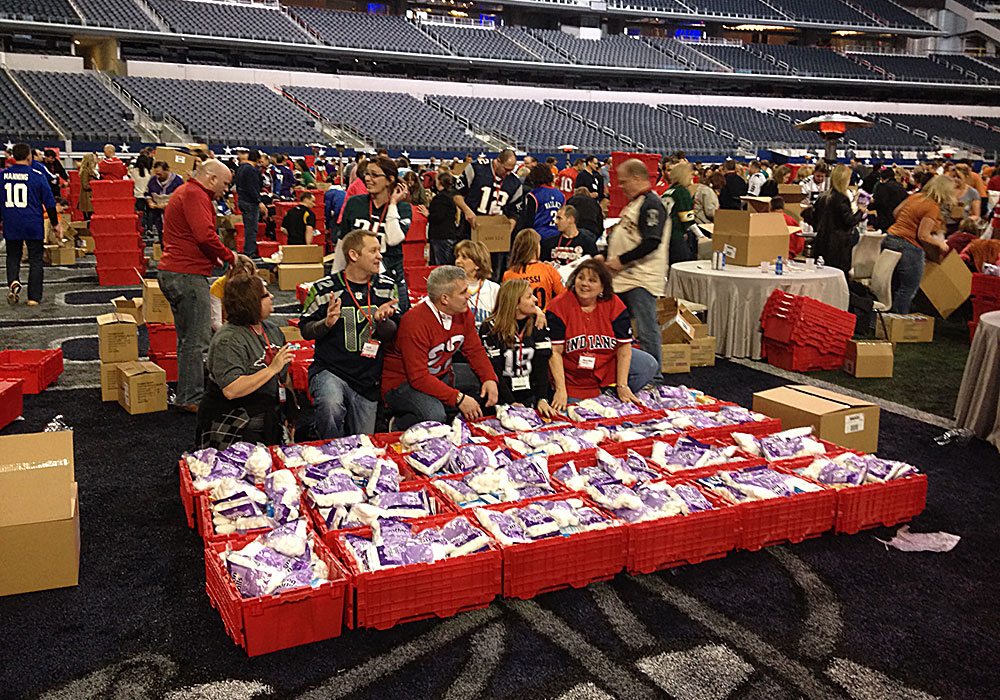 A group of people standing around a stadium with boxes of food.
