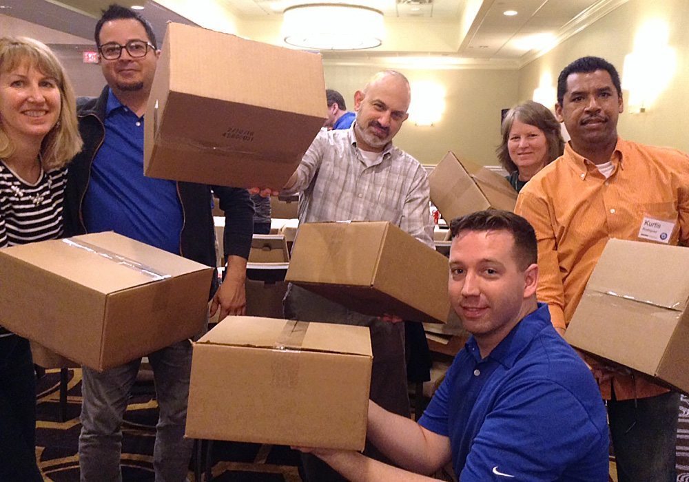 A group of people holding boxes in a room.