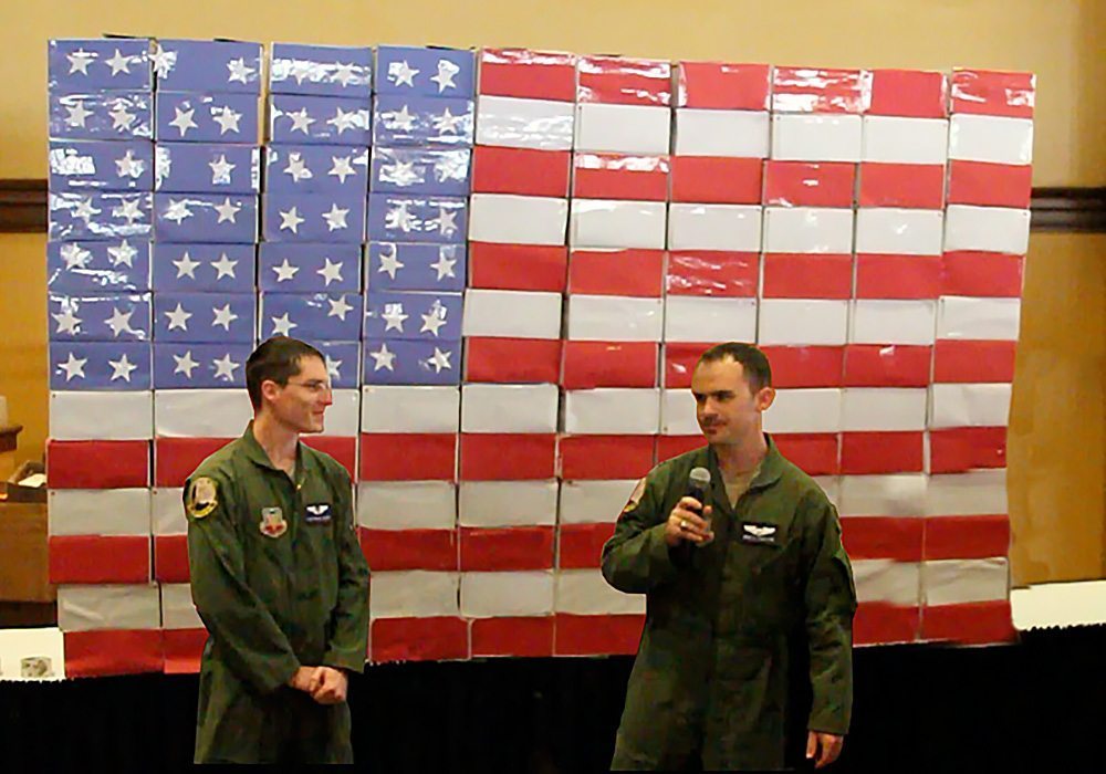 Two men standing in front of an american flag.