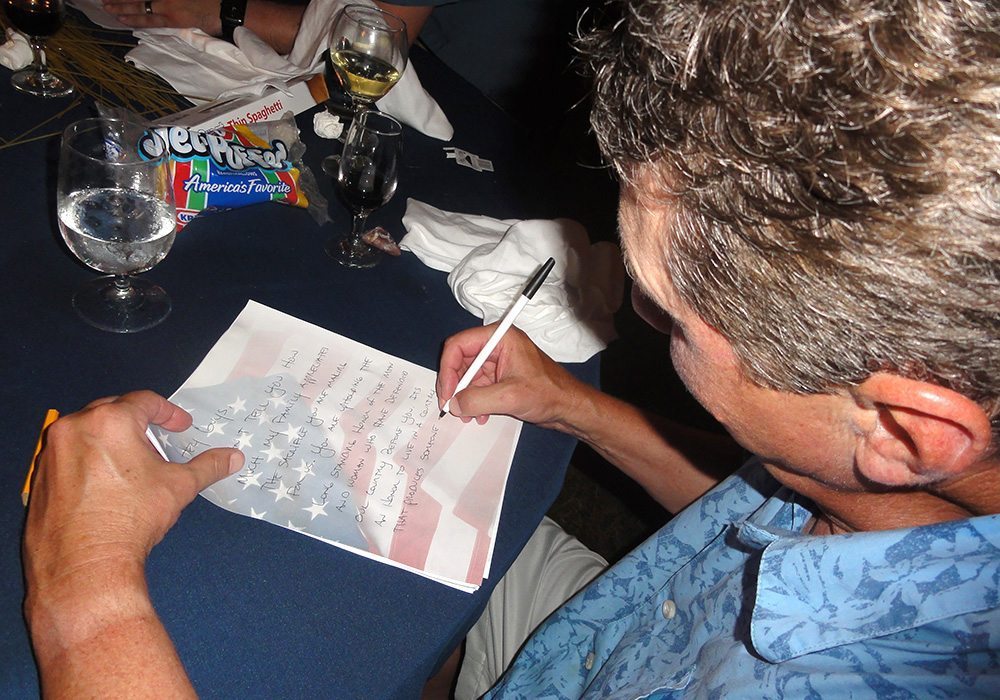 A man signing a piece of paper at a table.