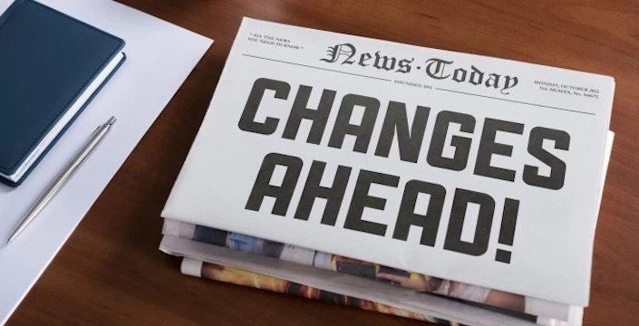 A newspaper with the word changes ahead sitting on a desk.