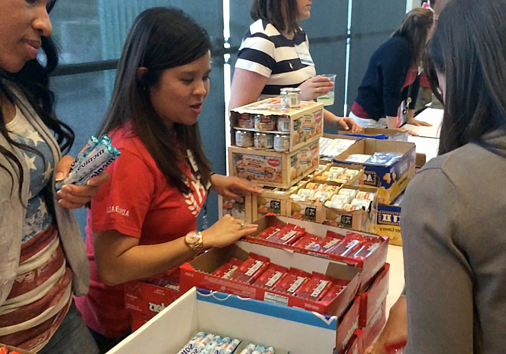 A group of people standing around a table with boxes of candy.