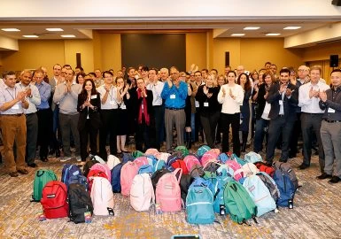 A group of people posing with backpacks in front of them.