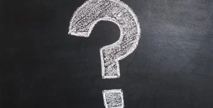 A question mark is drawn on a blackboard by a team.