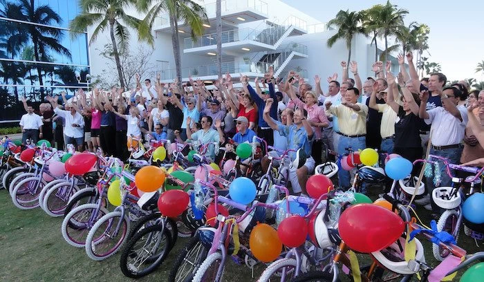 A group of people standing in front of a group of bicycles, celebrating #GivingTuesday.