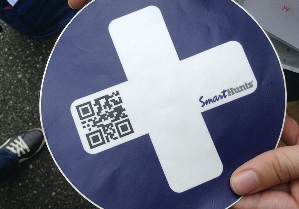 A person holding a sticker with a qr code on it.
