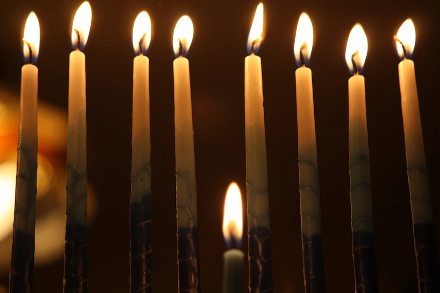 A group of hanukkah menorahs lit up in the dark, illuminating the surroundings.