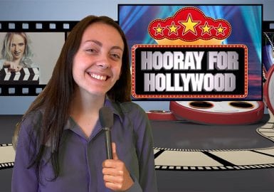 A woman is standing in front of a screen with the words hooray for hollywood.