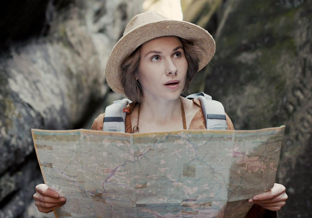 A woman in a hat is holding a map.