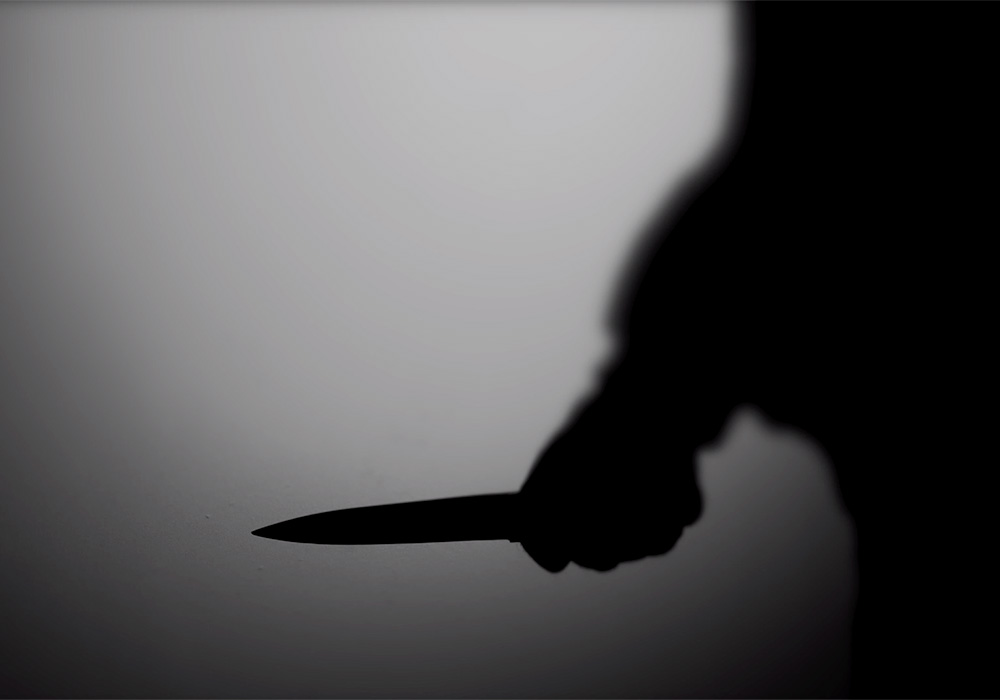 A silhouette of a person holding a knife.