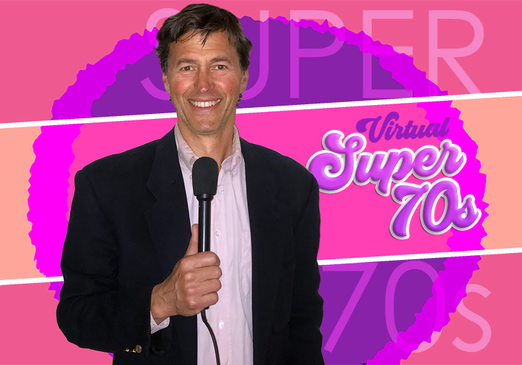 A man in a suit is holding a microphone in front of a pink background.