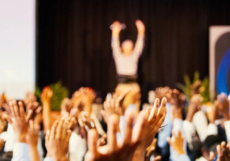 A group of people engaged in CSR activities, raising their hands at a team building conference.