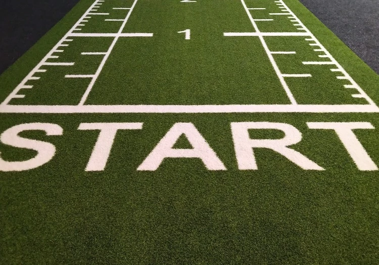 A football field with the word start written on it, promoting team building and employee orientation.