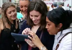 A group of people engaging in Best Corporate Events while looking at a tablet computer.