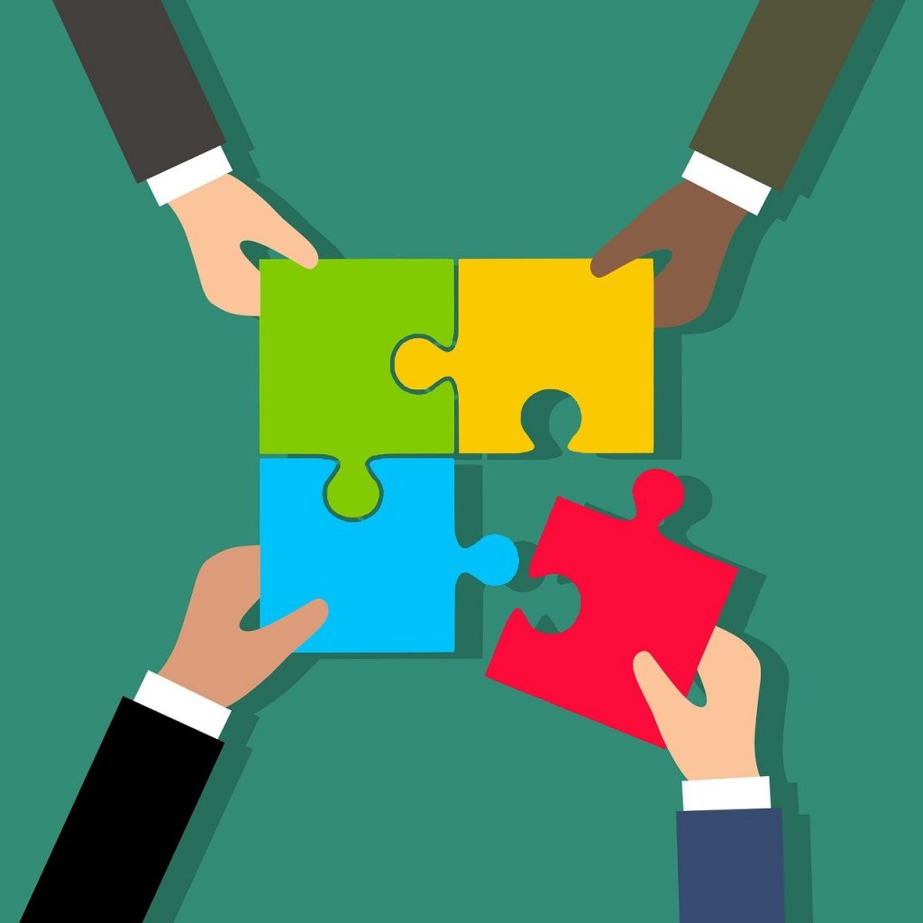 A group of corporate hands holding a puzzle piece together in a show of event partnerships.